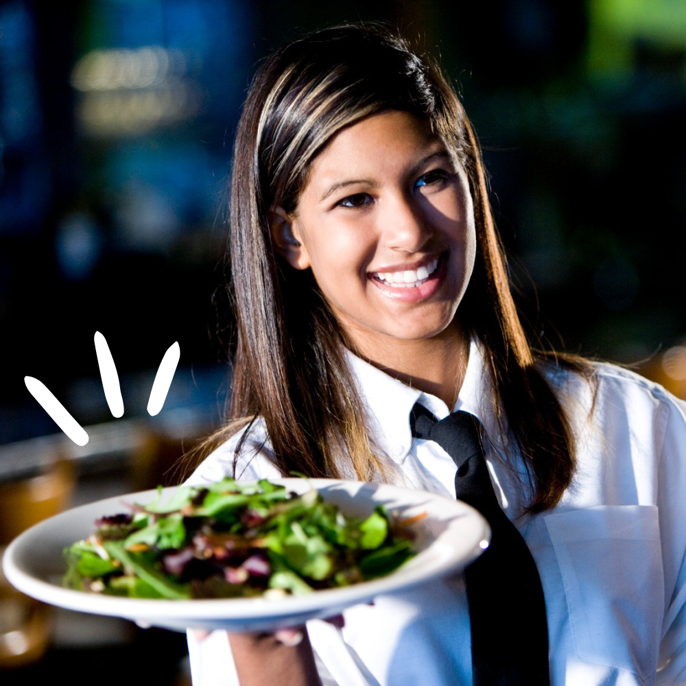 A photo of a female waitress who is carrying a plate of salad prepared with good food handling hygiene. 