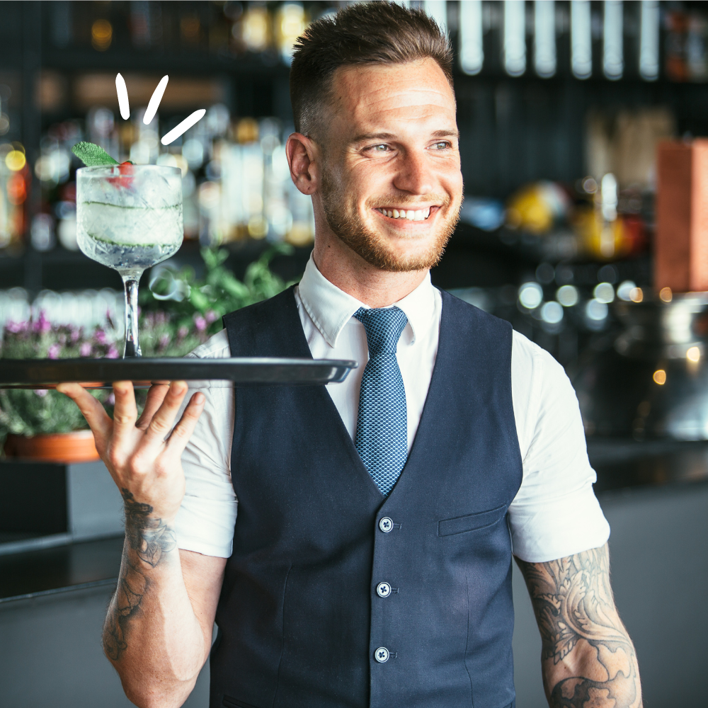 A photo of a bartender holding a tray with a cocktail on it that he made using his bartending skills. 