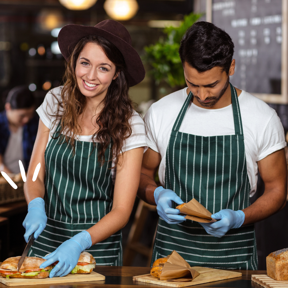 A waitress and a waiter preparing food in a cafe. 