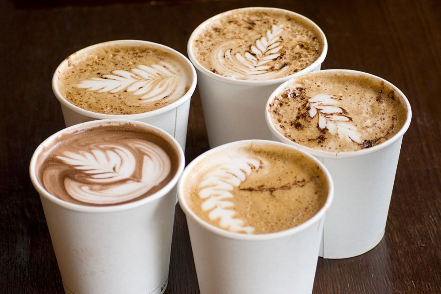 Photo of five coffees in takeaway cups made during a team building barista course..